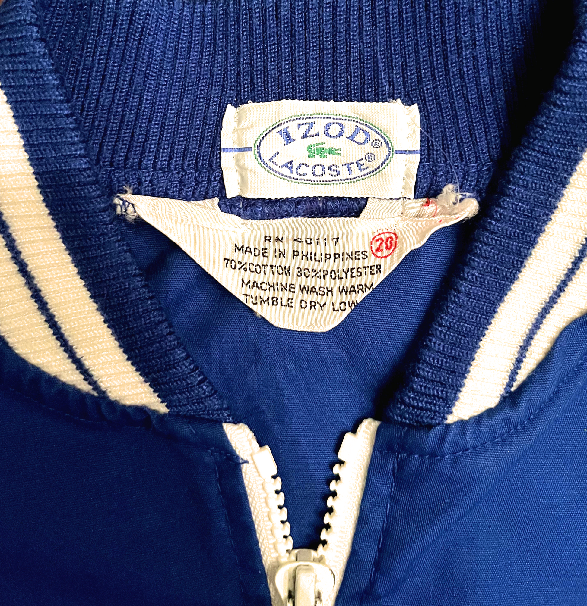 Tag of blue Lacoste jacket photographed laying down.