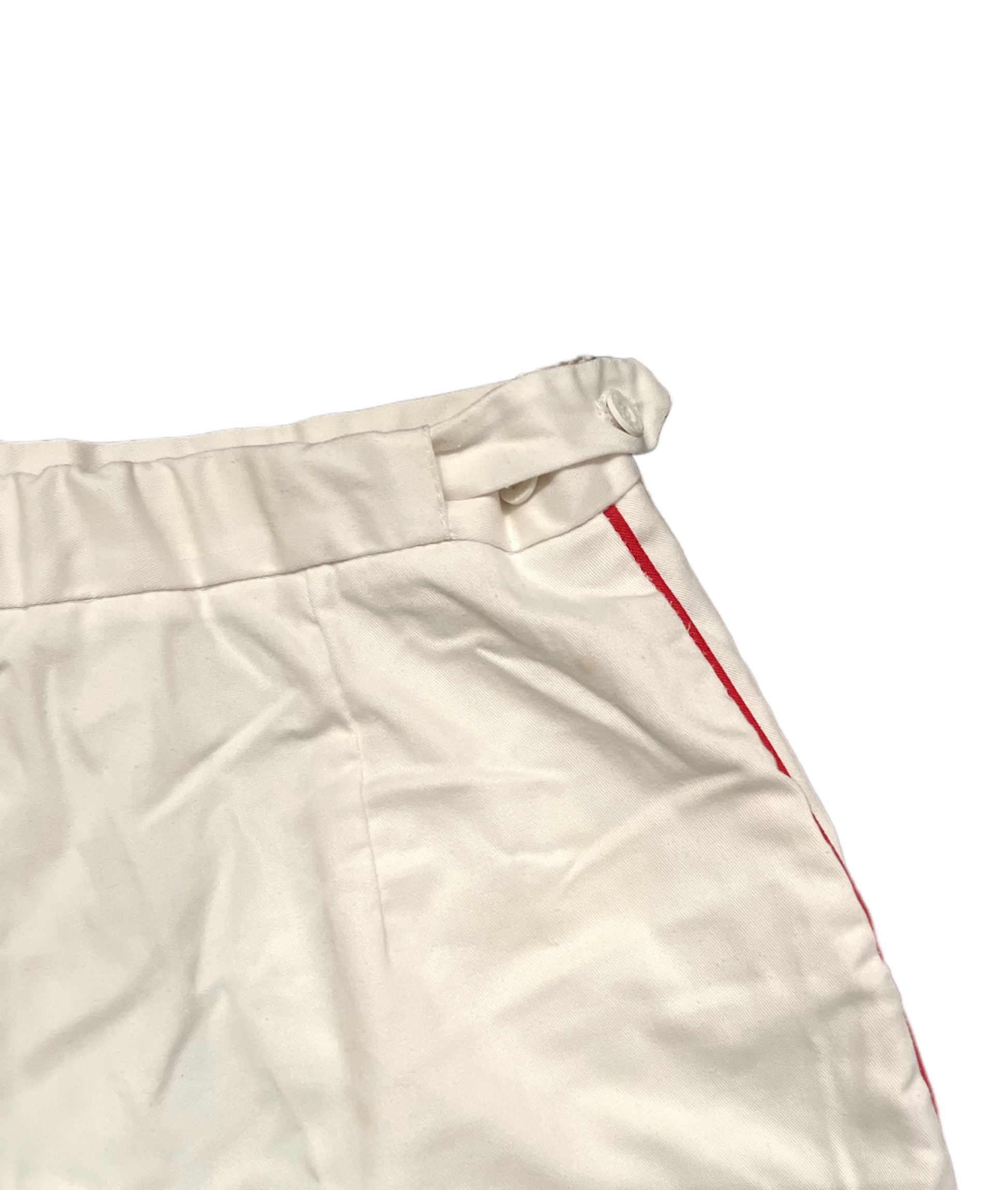 Adjustable waist band of white shorts with red stripe on white background.