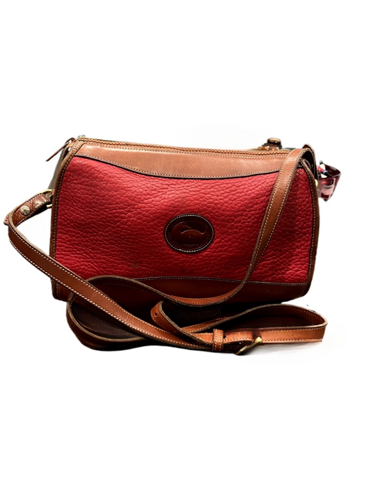 Front view of red Dooney & Bourke purse with tan leather strap on white background.