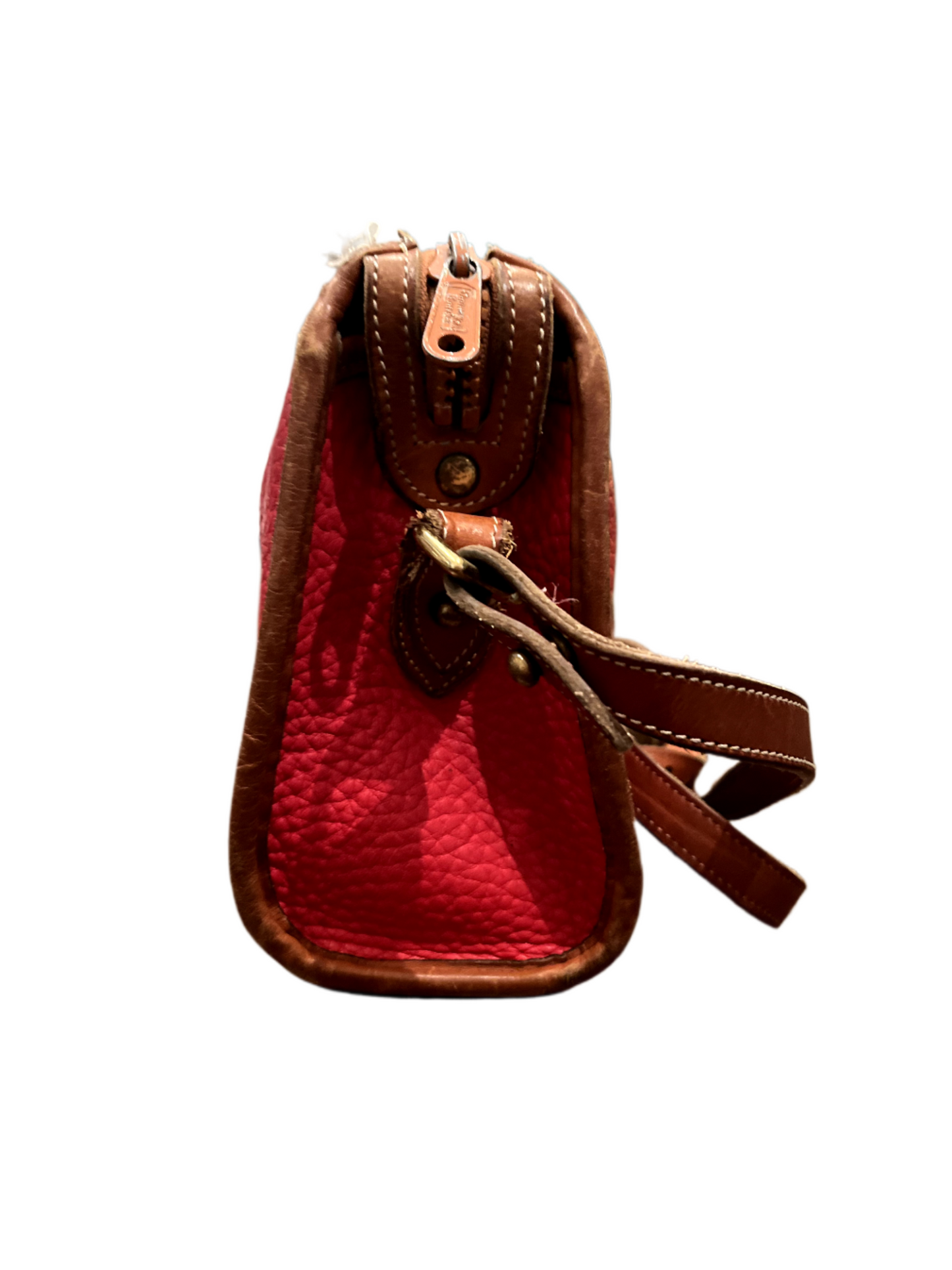 Side view of red Dooney & Bourke purse with tan leather strap on white background.
